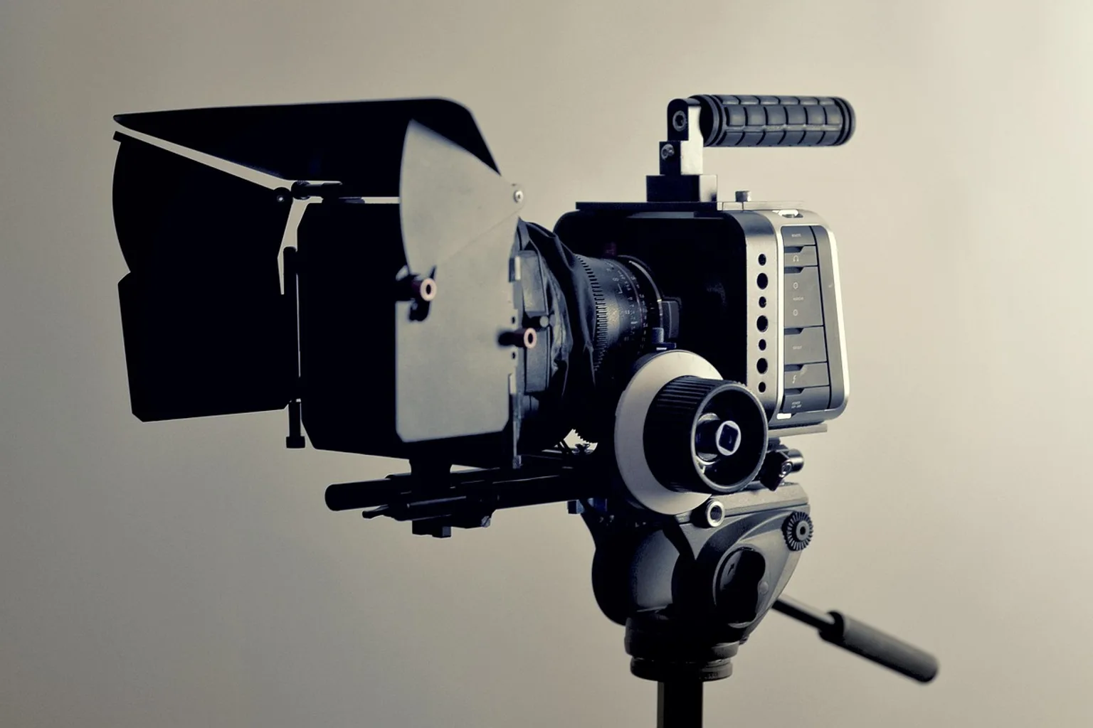 A cinema camera rig with matte box and follow focus mounted on a tripod, set up for a video promo shoot